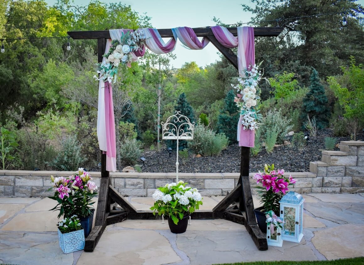 Floral wedding arch with pink drapery on a stone patio at Willow Creek Inn.