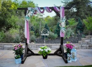 Floral wedding arch with pink drapery on a stone patio at Willow Creek Inn.